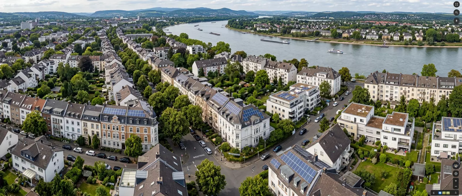 Luftaufnahme von Bonn am Rhein zeigt Wohnviertel mit begrünten Straßen und zahlreichen Dächern mit Solarmodulen.